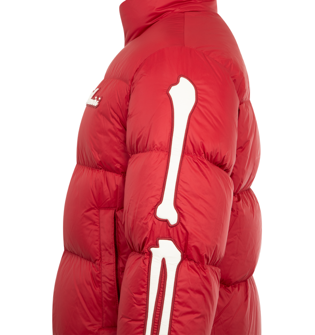 Image 3 of 3 - RED - AMIRI Bones Down Puffer Jacket featuring a logo at the chest, signature bone graphics on each sleeve, stand collar, drop shoulders, long sleeves, elasticized cuffs, waist zip pockets and two-way front zip closure. 100% nylon.