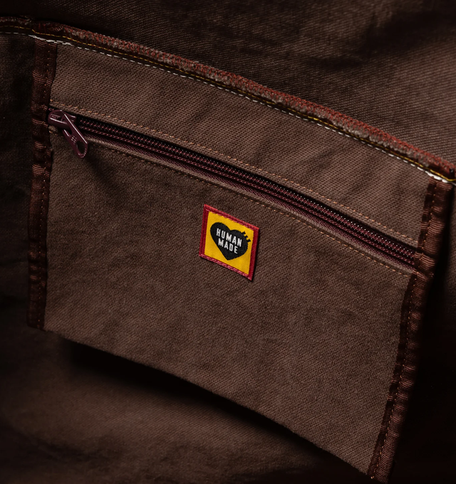 Image 7 of 8 - BROWN - HUMAN MADE Canvas Boston Bag Large featuring thick, tough cotton canvas, bio-washed for a vintage-like feel, graphics appear on both sides, external pocket and an internal zip pocket, heart-shaped rivets and 100L capacity. 100% cotton.