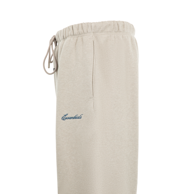 Image 3 of 3 - NEUTRAL - Fear of God ESSENTIALS Men's Signature Flare Sweatpant is crafted from heavyweight 380 GSM cotton-blend fleece and features a relaxed-fit silhouette that extends into a flared leg. Designed with the Essentials signature logo embroidered at the leg, this elevated loungewear style is finished with an encased elastic waistband, elongated drawcords, side-seam pockets, and a signature Essentials label at the center front. Main Material: 80% Cotton, 20% Polyester, 380 GSM.