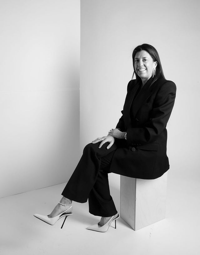 Marci Penn Hirshleifer in a black suit and white pointed toe stiletto heels 