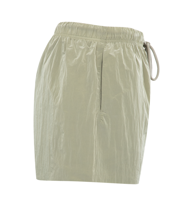 Image 3 of 3 - GREEN - FEAR OF GOD ESSENTIALS Running Short featuring an encased elastic waistband with elongated drawstrings, cropped length, side seam pockets and a rubberized label at the center front. 100% nylon.  