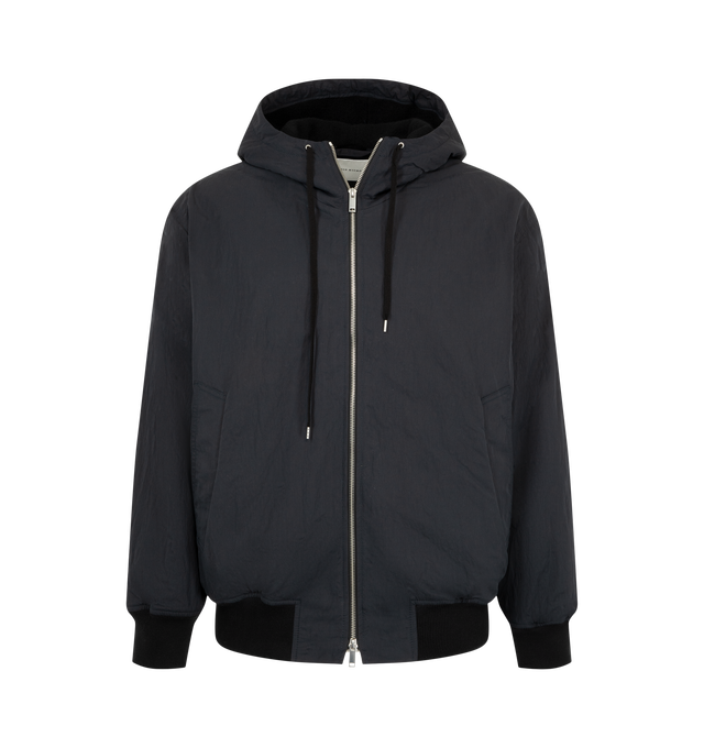 Image 1 of 3 - BLACK - Studio Nicholson Men's Wickett Jacket is crafted from Italian-milled water-repellent technical fabric and features a relaxed silhouette with a drawcord hood and soft rib-knit trims. Designed as an elevated interpretation of a classic sportswear staple, this versatile jacket is lined in a warm wool blend for added comfort and insulation while maintaining a clean, understated appearance. Main Material: 100% Polyamide. Lining: 70% Wool, 30% Polyamide.