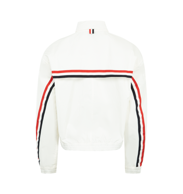 Image 2 of 4 - WHITE - THOM BROWNE Nylon Tech Track Jacket featuring front hidden two-way zip closure, stand collar lined with RWB grosgrain, ripstop drawstring hood that folds into collar with hidden zip, welt hand pockets with hidden snap, back storm flap over mesh panel, RWB grosgrain trim along storm flap and back sleeves, elasticated cuffs and hem with channel stitching and signature striped grosgrain loop tab. 51% polyamide, 49% cotton. Made in Italy.
