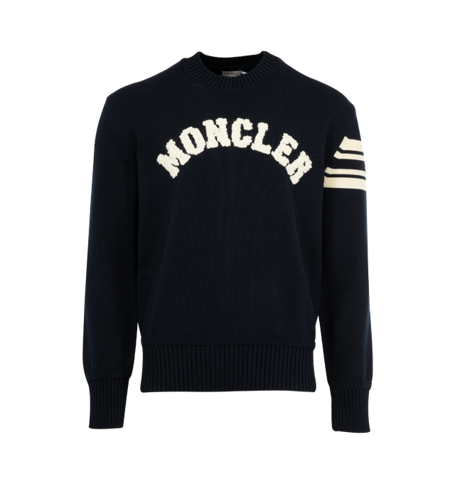 Image 1 of 3 - NAVY - MONCLER Curved Logo Knit Crewneck Sweater featuring embroidered curved logo on the front, logo emblem with stripes on the left sleeve, crew neckline, long sleeves, ribbed cuffs and hem and pullover style. Polyester/leather. Lining: polyester. Made in Bulgaria.