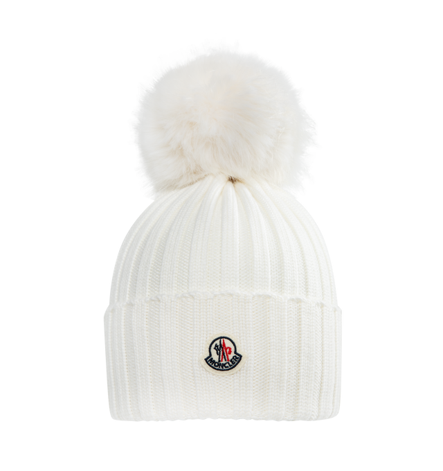 Image 1 of 1 - WHITE - MONCLER Wool Beanie with Pom Pom features an English rib-knitting and logo at front and embellished with a faux fur pom pom. Designed to provide warmth, this heavy knit beanie for women adds the finishing touch to cold-weather looks. 100% virgin wool .