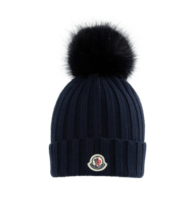 Image 1 of 2 - NAVY - MONCLER Wool Beanie featuring ultra-fine Merino wool, faux fur pom pom, rib knit and Gauge 5. 100% virgin wool. Made in Bulgaria. 