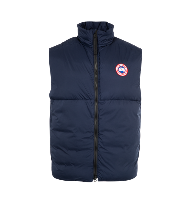 Image 1 of 2 - NAVY - CANADA GOOSE Lodge Vest featuring rip-stop construction, hip length, down-filled collar with a draw cord to seal out drafts, YKK two-way locking reversed coil zipper front closure, with logo pull, insulated wind guard under front zipper, brushed tricot at the chin and behind the neck, single-handed adjustable hem using pocket access to seal out cold and wind, zip hand pockets, and an inside stretch mesh pocket. Made in Canada.