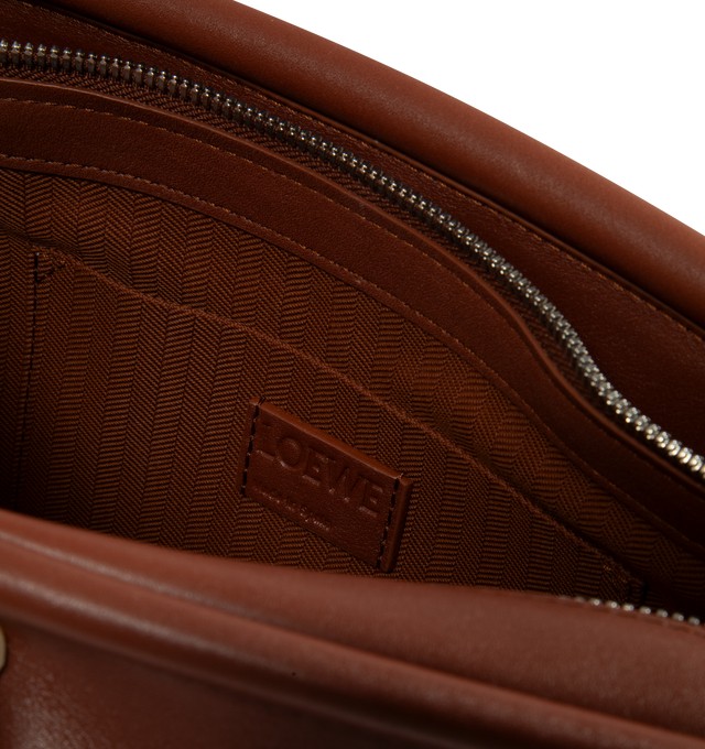 Image 3 of 3 - BROWN - Loewe Small Whisker Bag is crafted from black glazed calfskin and features a slouchy silhouette with a structured handle and oversized zip opening. Designed for shoulder, crossbody, or hand carry, it includes a detachable strap with rotating dog clips, articulated zipper pulls, foldable D-rings, an exterior flat pocket, and an interior flat pocket. Gold-tone hardware and embossed Loewe and Double L branding complete the design. Fits a large phone, small wallet, sunglasses, and keys. M