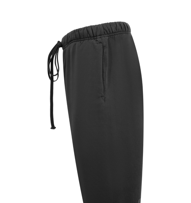 Image 3 of 3 - BLACK - FEAR OF GOD ESSENTIALS Heavy Fleece Flare Sweatpant featuring 520gsm heavy fleece treated with a pigment dye to create rich depth of color, relaxed, flared-leg, HD-printed graphics on back of legs, encased elastic waistband with elongated drawcords, side seam pockets and a Fear of God Essentials label stitched at the center front. 100% cotton.