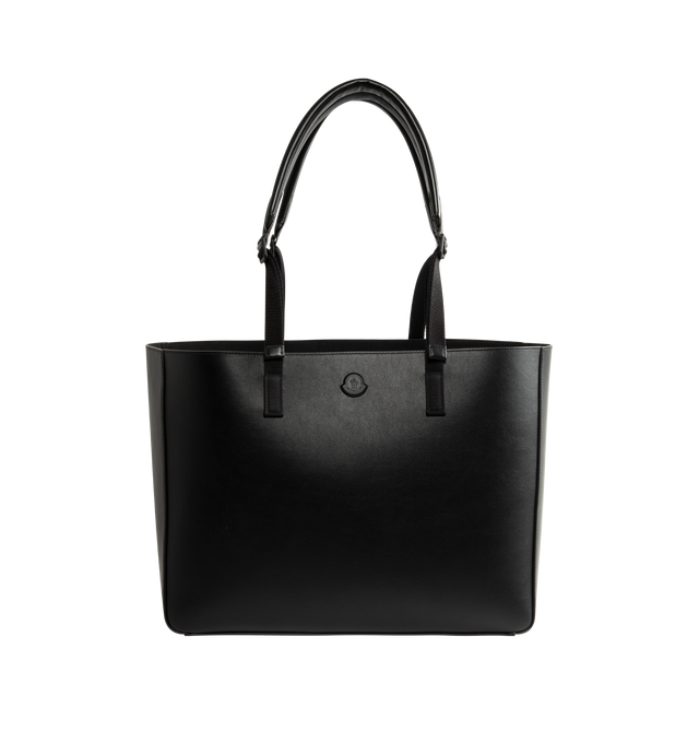 Image 1 of 3 - BLACK - Moncler Men's Carlo Leather Tote Bag is crafted from supple calf leather and features a spacious, clean-lined silhouette designed for versatile everyday use. Finished with adjustable leather handles, an interior pocket with snap-button closure, embossed and metal Moncler logo details, and a stretch polyester-blend lining, this designer tote combines refined craftsmanship with practical organization. Leather Exterior: Cow Leather. Lining: 91% Polyester, 9% Elastane/Spandex. Dimensions: