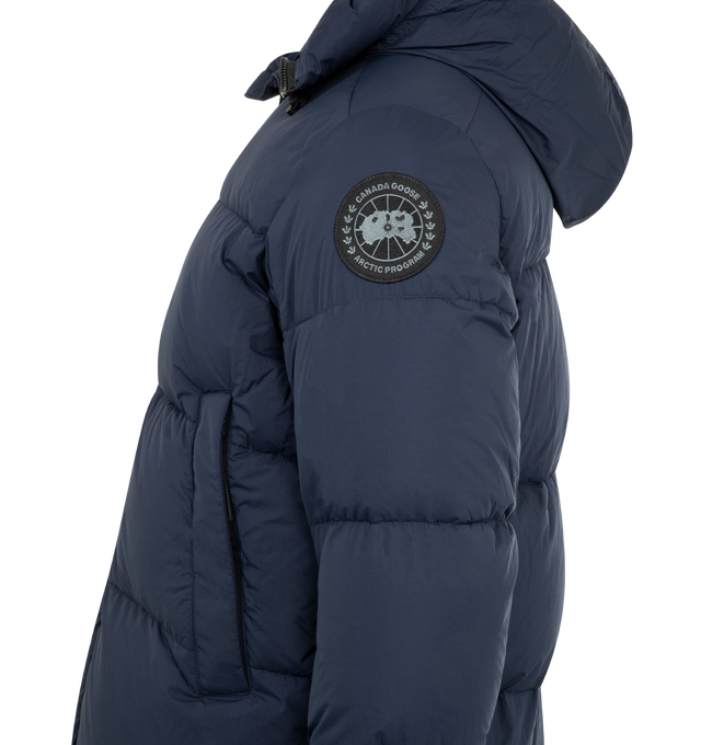 Image 3 of 3 - NAVY - CANADA GOOSE Crofton Puffer featuring an adjustable hood, a drawcord at the hem to customize the fit and lock in warmth, packable into interior left pocket, converts into a cinchable bag with a carrying strap, down-filled adjustable hood with drawcord, two-way zipper, recessed rib-knit cuffs, two fleece-lined zippered hand pockets and two interior mesh drop-in pockets. 100% recycled polyamide. Made in Canada.