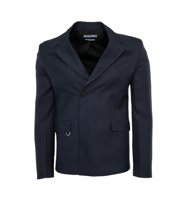 Image 1 of 3 - NAVY - JACQUEMUS LA VESTE MELO is a double-breasted tuxedo blazer with a straight fit with structured shoulders, notched tuxedo lapel, double-breasted with single visible button, buttoned cuffs, flap welt pockets, d-ring on the right pocket, satin lapels and piping. 100% virgin wool 