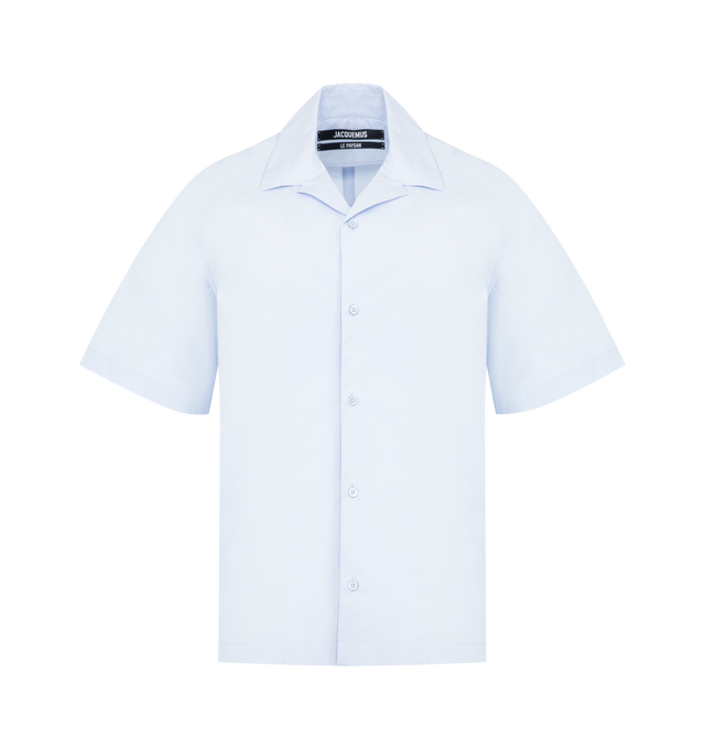 Image 1 of 2 - BLUE - JACQUEMUS Fonccio Shirt featuring relaxed fit, cotton poplin, camp collar, boxy elbow-length raglan sleeves, back yoke, large embroidered J on the the back and Mother-of-pearl buttons. 100% cotton. Made in France.