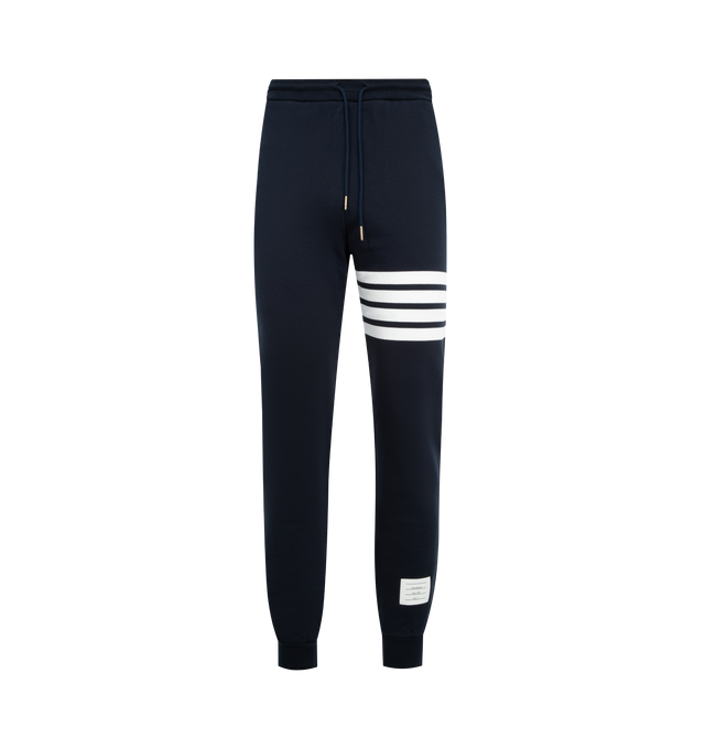 Image 1 of 3 - NAVY - THOM BROWNE Classic Loopback 4 Bar Sweatpant featuring iconic 4-Bar detailing, drawstring waistband with silver tone aglets, slip side pockets, single back welt pocket, name tag applique above left cuff and signature striped grosgrain loop tab at back waist. 100% cotton. Made in Japan.