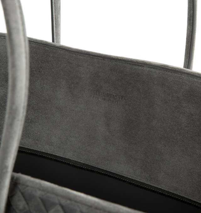 Image 3 of 3 - GREY - Bottega Veneta Women's Large Intrecciato Suede Tote Bag is crafted from supple Intrecciato suede and features a streamlined silhouette, a single-compartment interior, and a zip-top closure. Designed with snap-button attachments for the Dustbag Organizer system, it is finished with one interior zip pocket, an internal hand mirror with a leather cover, lambskin lining, and silver-finish hardware. Main Material: Intrecciato Suede. Lining: Lambskin. Hardware: Silver Finish. Made in Italy.