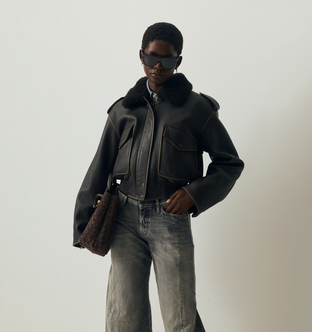 Image 2 of 5 - BROWN - ACNE STUDIOS Leather Bomber Jacket featuring soft lamb leather with a shearling collar, dropped shoulders with epaulettes, front flap pockets, side welt pockets, an elasticated hem, front snap button, zipper closure, zip sleeves, a metal logo plaque at the back neckline, relaxed fit and below-waist length. 100% Lamb leather. 100% Lamb shearling. Lining: 100% viscose.