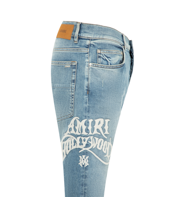 Image 3 of 3 - BLUE - Amiri Mens Hollywood MX1 Jeans are crafted from stretch denim with a hand-distressed finish. Feature a slim fit, five-pocket styling, pleated denim repair panels, satin embroidered detailing, button and zip closure, and signature MX1 construction. Main Material: 92% Cotton, 6% Elastomultiester, 2% Elastane. Made in Italy.