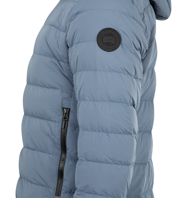 Image 3 of 3 - BLUE - CANADA GOOSE Crofton Hoodie EnduraLuxe Jacket featuring two-way zipper, packable into interior left pocket, converts into a cinchable bag with a carrying strap, adjustable hood with hidden drawcord, removable interior backpack straps for hands-free carrying capabilities, interior drawcord at hem, wo exterior tricot-lined zippered hand pockets and one interior drop-in pocket. 100% recycled polyamide. Made in Canada.