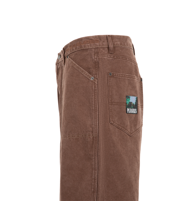 Image 3 of 3 - BROWN - Pleasures Men's Ultra Work Shorts are crafted from durable cotton canvas and feature a relaxed, baggy workwear-inspired silhouette. Designed with a zip fly, metal shank button closure, and reinforced metal rivets, the shorts are finished with contrast stitching at the front pockets and a woven logo patch at the back pocket. Main Material: 100% Cotton Canvas.