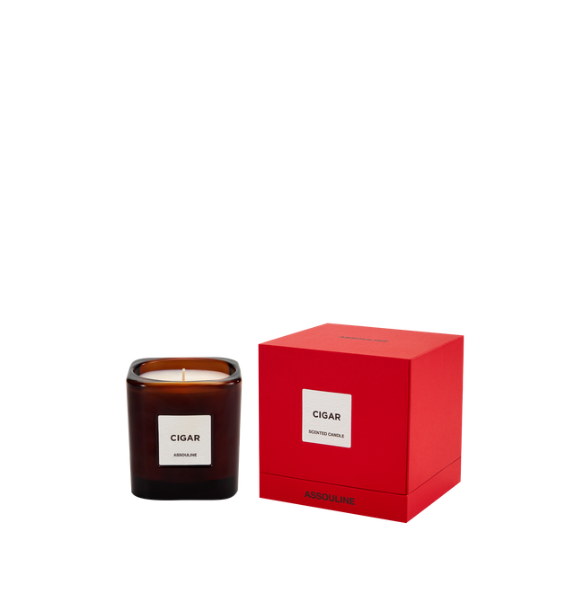 Image 1 of 3 - RED - Assouline Library Candle Cigar is a luxury scented candle that captures the warm, sophisticated ambiance of a Havana lounge with an oriental fragrance blending cedar, clove, patchouli, amber, and tonka bean. Housed in a heavyweight amber glass vessel with a textured paper label, this designer candle is crafted from a premium soy, coconut, and paraffin wax blend for a clean, even burn and exceptional scent throw. Top Notes: Allspice, Damask Rose. Heart Notes: Jasmine, Cedarwood. Base No