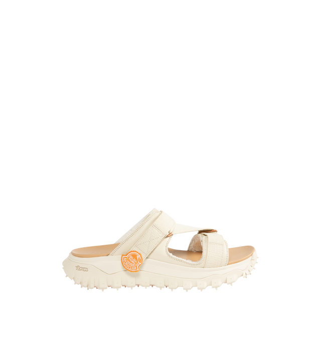 Image 1 of 4 - WHITE - Moncler x Gilga Farm Designed by Donald Glover Trailgrip Vela Leather Sandals featuring upper in leather and cotton, faux fur insole, EVA midsole, special Vibram MEGAGRIP rubber compound tread, EVA ergonomic insole and strap closure. Sole height 4.5 cm. Upper: 100% cotton. 100% cow. Lining: 100% polyester. Sole: 100% elastodiene. Made in Vietnam.