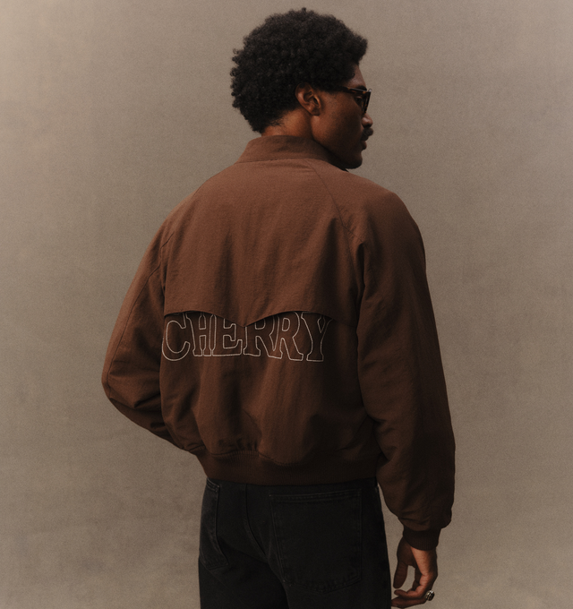Image 7 of 7 - BROWN - Cherry LA Nylon Championship Jacket is crafted from nylon and features a regular-fit silhouette, a front nickel zip closure, and rib-knit cuffs and hem. Designed with a brushed cotton lining, welt pockets with hidden snap closures, and embroidered detailing at the neck and center back, this lightweight jacket draws inspiration from classic championship styles with a contemporary finish. Main Material: Nylon. Lining: Brushed Cotton. Made in Los Angeles, USA.