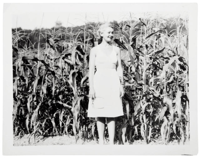 Black and white Hirshleifer family photo - a woman wearing a dress standing in a corn field 