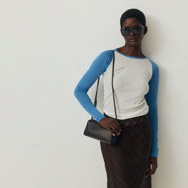 Woman wearing blue and white basbeall tee by Auralee with The Row 90's bag 