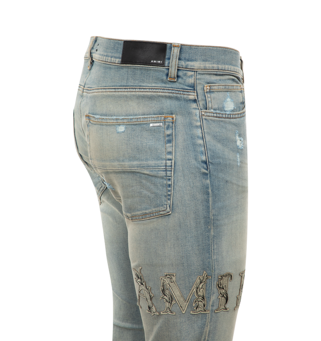 Image 2 of 2 - BLUE - AMIRI Baroque Logo Jeans featuring faded denim, belt loops, regular rise, five-pocket style, embroidered logo lettering at right thigh, full length and slim fit. Cotton/elastane. Made in USA. 