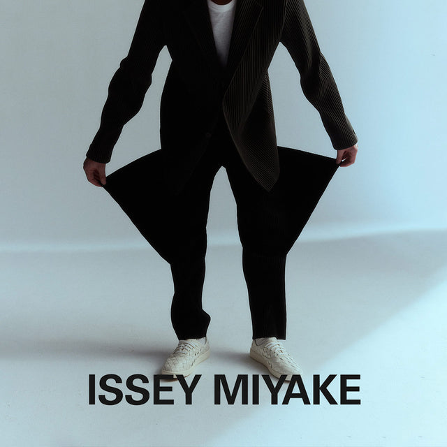 Man wearing Issey Miyake black plisse jacket and pants. Shop Issey Miyake online.