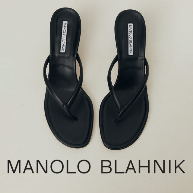 Black sandals with 'Manolo Blahnik' branding on a light gray background 
