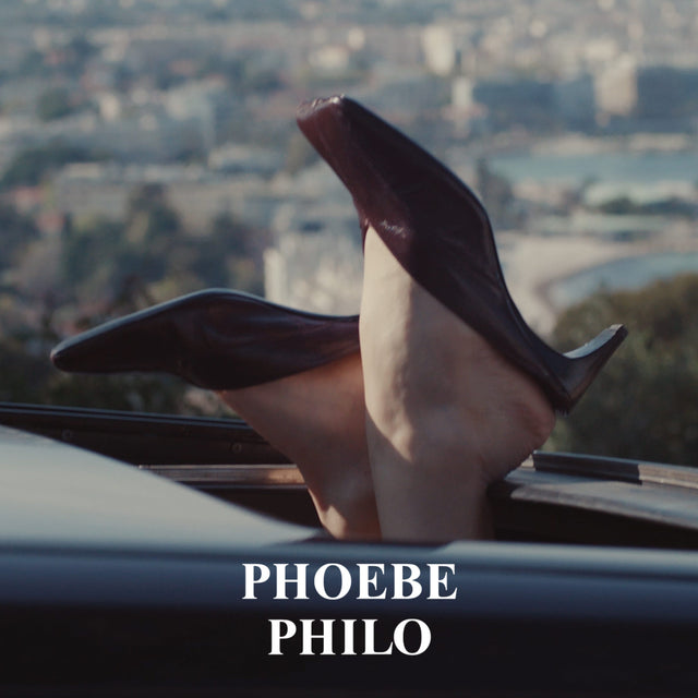 Phoebe Philo campaign featuring black high-heeled shoes with a cityscape in the background, featuring the brand 'Phoebe Philo'. 