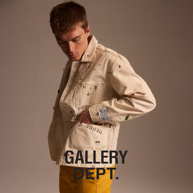 Man wearing Gallery Dept. white painter jacket and yellow chino pants, available online