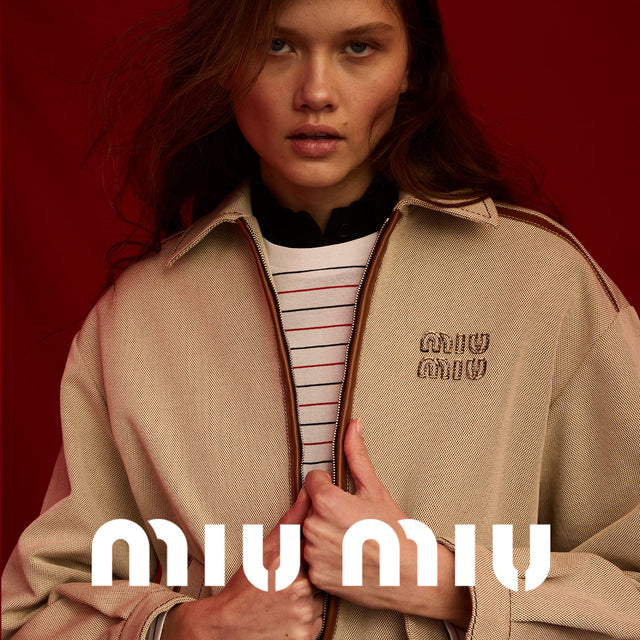 Woman wearing light brown bomber jacket with Miu Miu logo at the chest