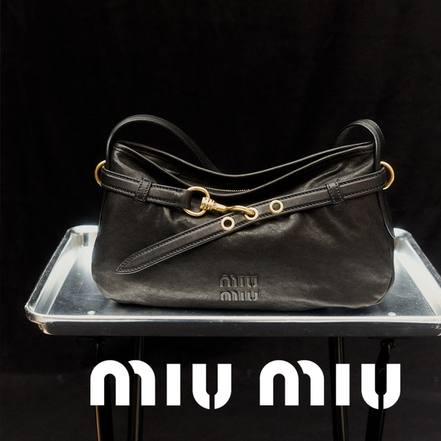 Black handbag with gold accents  featuring the Miu Miu logo. 