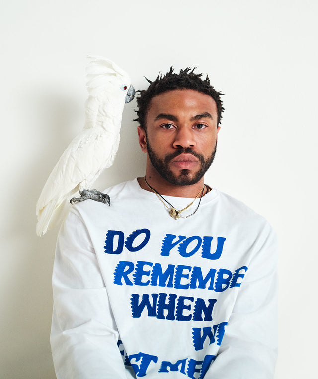 Man wearing white long-sleeve shirt with blue text "DO YOU REMEMBER WHEN WE FIRST MET?" from the Loewe Paula's Ibiza collection 