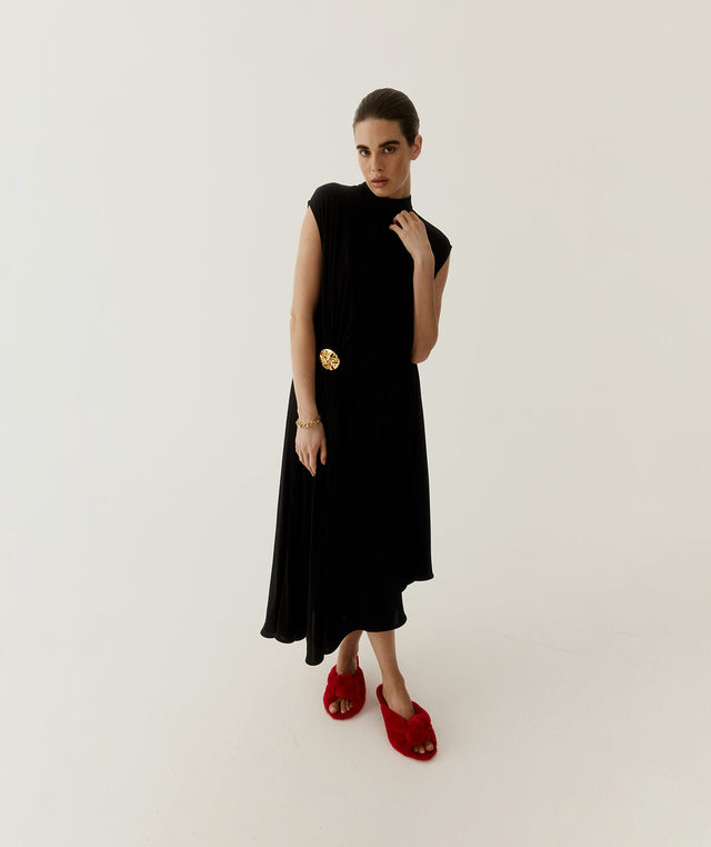 Woman wearing a black sleeveless dress with a gold detail by Bottega Veneta 