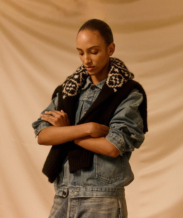 Person wearing a Chimala denim jacket, jeans and a fair isle sweater around her neck 