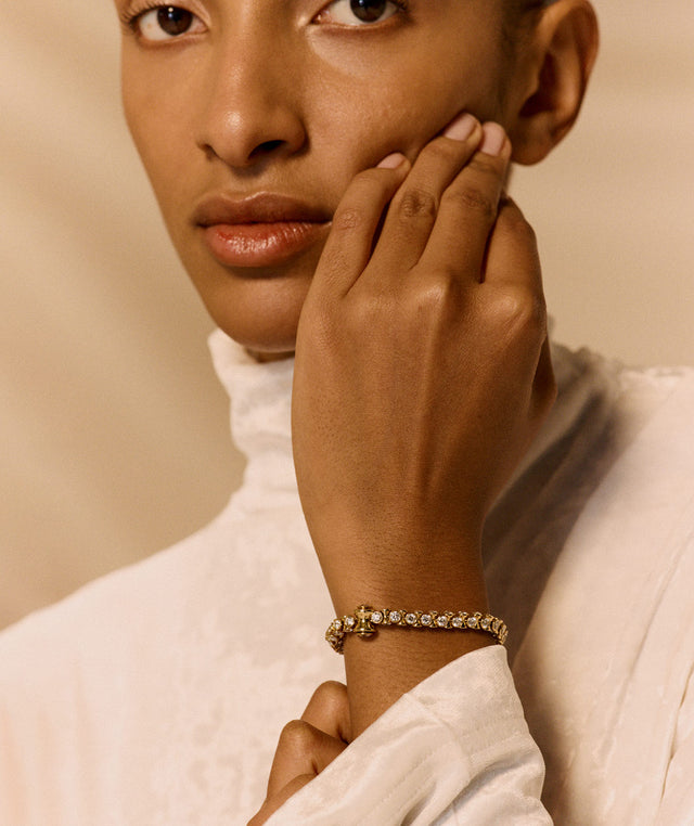 Woman wearing a gold and dimaond bracelet by OX Jewelry on a beige background 