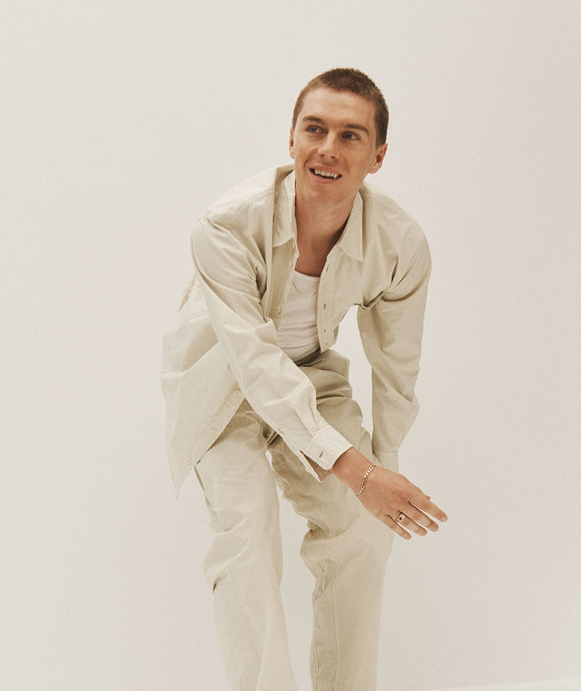 Man wearing off-white relaxed button-up shirt and drawstring pants by LeMaire 