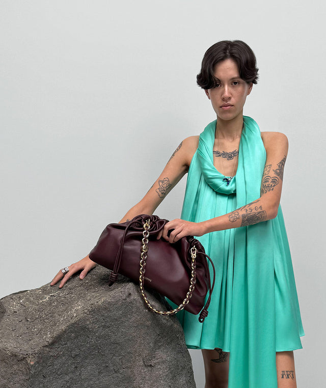 Woman in green dress holding brown flamenco bag with chain strap, by Loewe 