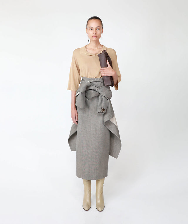 woman wearing THE ROW Laz Skirt featuring in grey wool knotted detailing at the hip with THE ROW Kenna  polo-style boxy fit top in tan viscose 