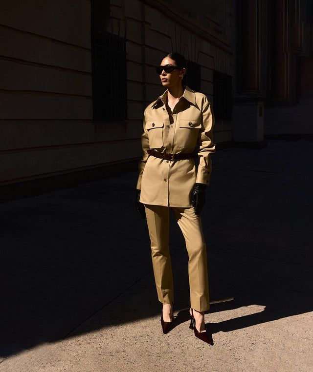 Woman wearing khaki drill shirt and twill pants with patent leather slingback heels, all by saint laurent  
