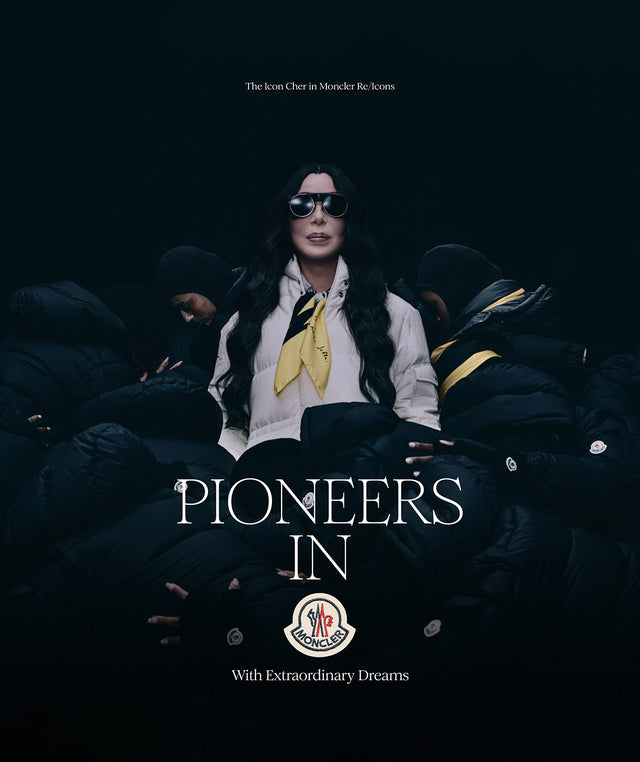 Cher wearing Moncler white puffer coat and yellow silk scarf. Text on image reads "The Icon Cher in Moncler Re/Icons. Pioneers in Moncler with extraordinary dreams/"  