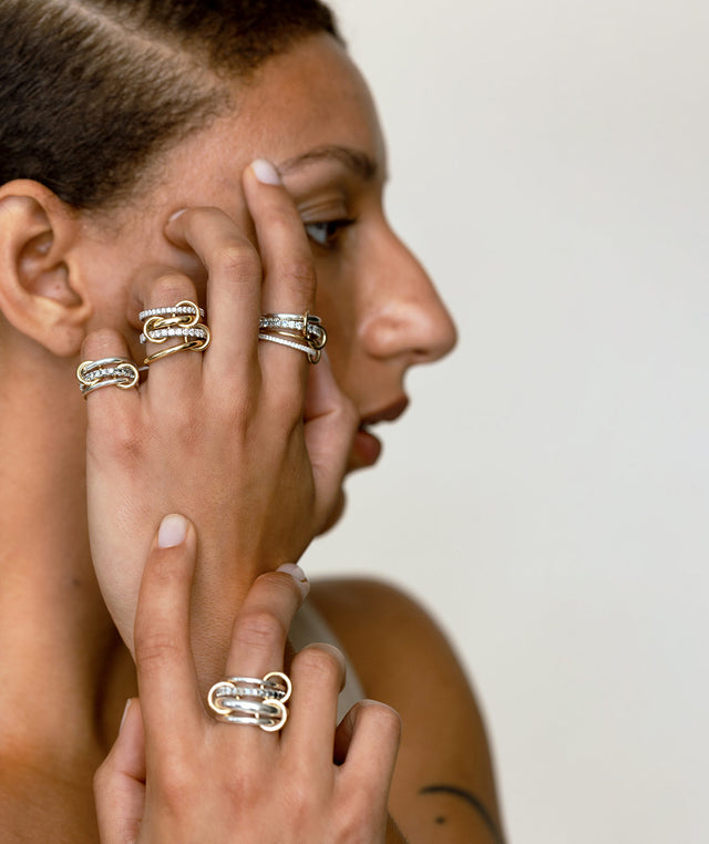 Woman wearing multiple Spinelli Kilcollin linked rings  