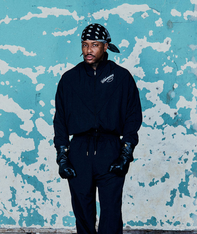 Man wearing WILLY CHAVARRIA Ruff Rider Track Jacket with bandana and leather gloves 