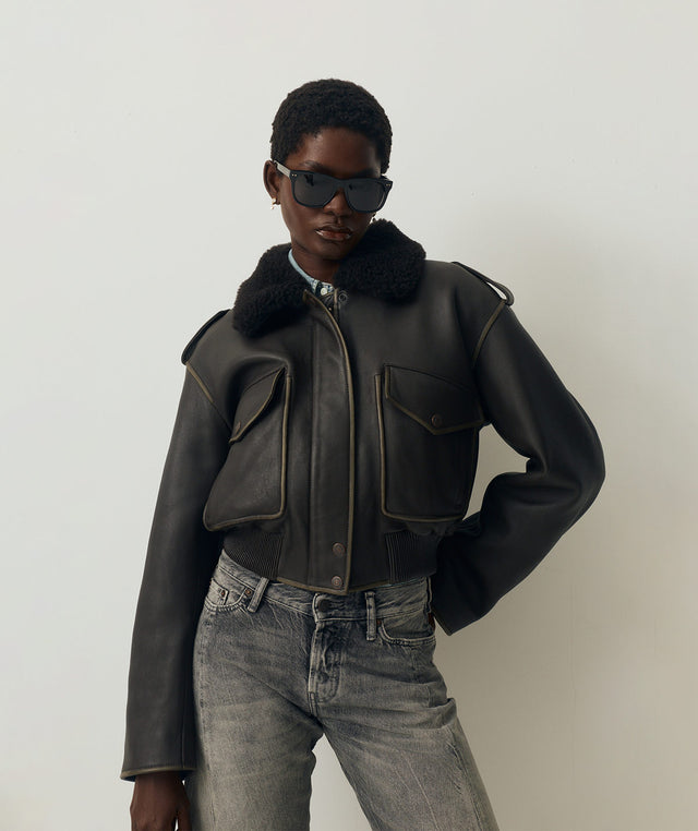 Person wearing an Acne Studios dark leather jacket with fur collar and Celine sunglasses 