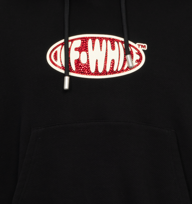 BLACK -  OFF-WHITE CRYST ROUND LOGO OVER HOODIE has the Off White logo in the center in an oval filled with red crystals, with a drawstring hood, wording on the back and kangaroo pockets. 100% cotton.