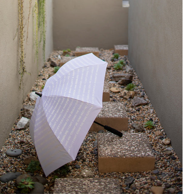 Image 4 of 4 - BLACK - Curves at Home Color changing umbrella transforms from all white when dry, to reveal lyrics from Missy Elliots The Rain in black lettering when wet. 100% polyester. Automatic push button. Length when closed: 12in/30.5 cm. Approx. 23" length. 