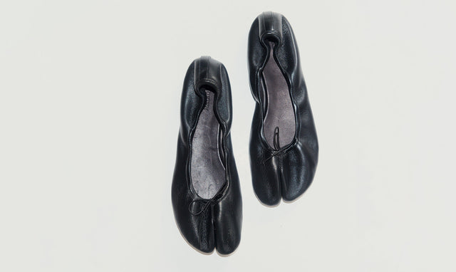 A pair of black leather tabi-style ballet flats by Christen with a split toe design, shown from a top-down view on a light gray background.
